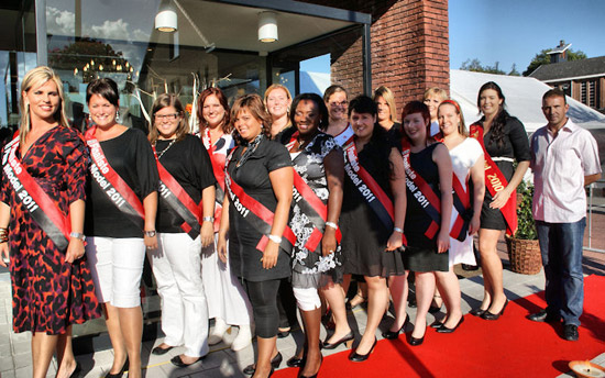 De groep finalisten voor de verkiezing van Miss Plus Model plaatsten de opening van de zaak in de juiste context. Inge Brocken leidt de groep en wielervedette Johan Museeuw sluit af als medewerker van een modehuis.