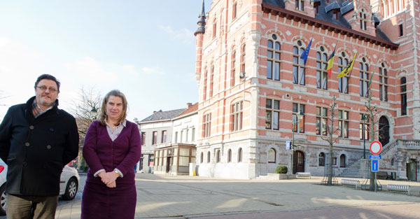 Schepen van Toerisme Franky De Graeve en toerismefunctionaris Beatrix Mys vóór 2 opnamelocaties van ‘Met Man en Macht’: het gemeentehuis en café Bij Rita op de Markt